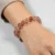 Tangerine Quartz crystal bracelet worn on woman's wrist, warm peachy-orange gemstone beads.