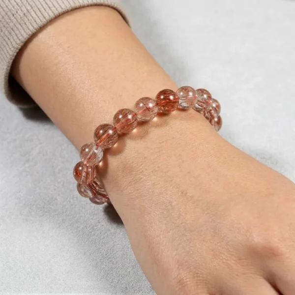 Tangerine Quartz crystal bracelet worn on woman's wrist, warm peachy-orange gemstone beads.