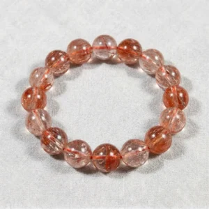 Tangerine Quartz crystal bead bracelet with natural orange-red rutile inclusions on gray background.