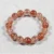 Tangerine Quartz crystal bead bracelet with natural orange-red rutile inclusions on gray background.
