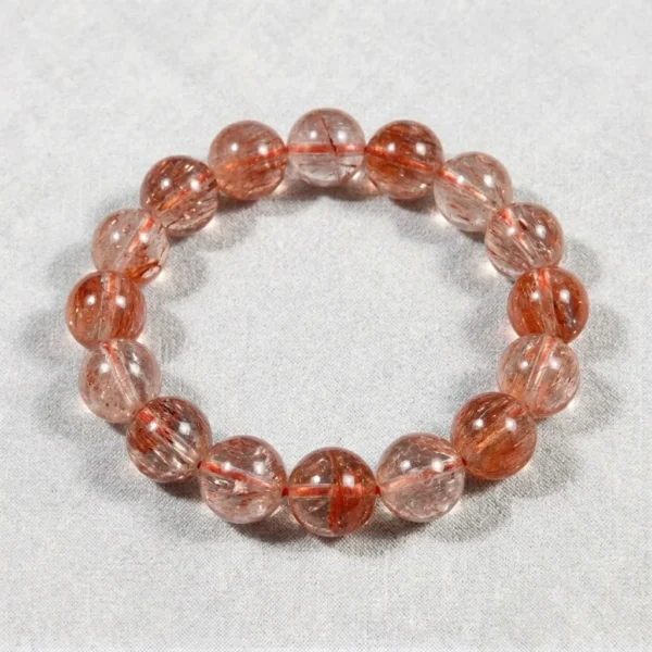 Tangerine Quartz crystal bead bracelet with natural orange-red rutile inclusions on gray background.