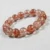 Close-up of Tangerine Quartz bracelet showing vivid orange-red fiber inclusions in polished round beads.