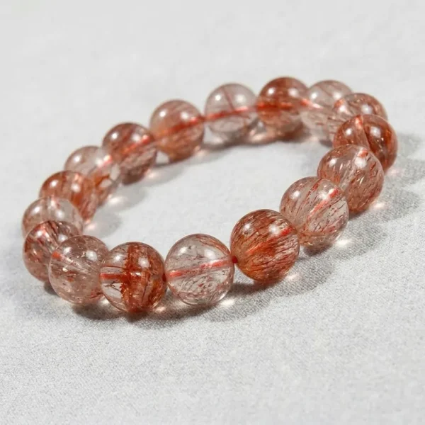 Close-up of Tangerine Quartz bracelet showing vivid orange-red fiber inclusions in polished round beads.