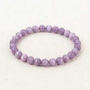 Kunzite Energy Bracelet with smooth lavender-purple crystal beads laid on off-white linen background.