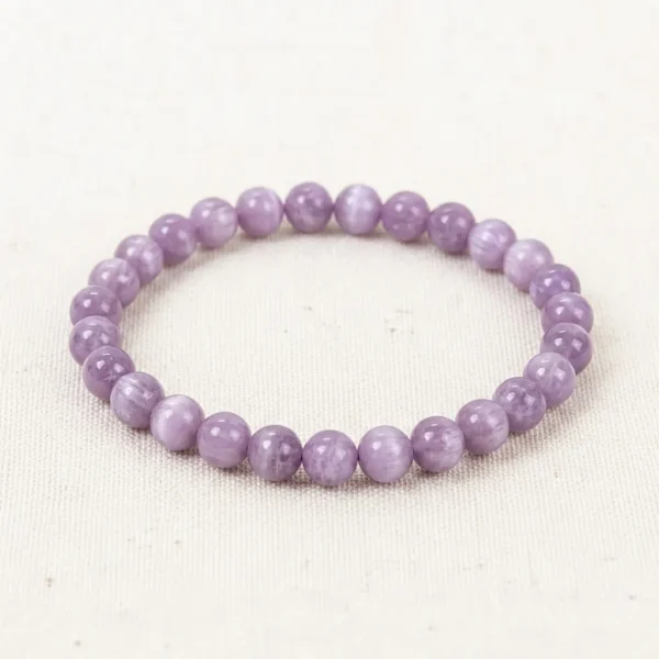 Kunzite Energy Bracelet with smooth lavender-purple crystal beads laid on off-white linen background.