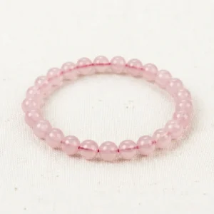 Rose Quartz Energy Bracelet with soft pink translucent beads on cream linen background.