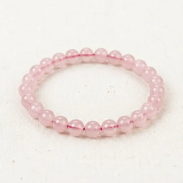 Rose Quartz Energy Bracelet with soft pink translucent beads on cream linen background.