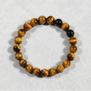 Yellow Tiger's Eye bracelet with one black obsidian accent on gray background.