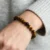 Yellow Tiger's Eye bracelet worn on wrist with single black bead, gray knit sleeve background.